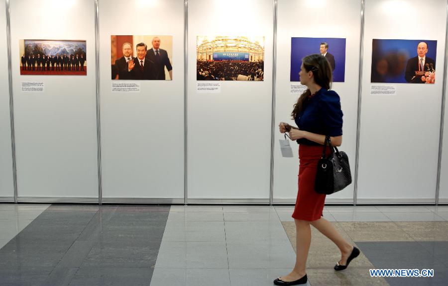 A visitor looks at photos on display during a photo exhibition of the first World Media Summit in Beijing, presented by Xinhua News Agency, in Russian capital Moscow on July 5, 2012. 