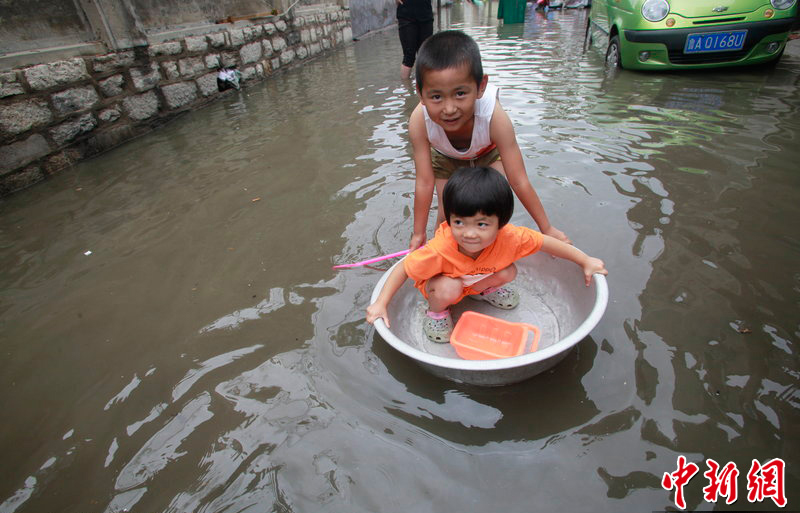 Rainstorms hit Jinan, Shandong Province, on July 8, 2012. In the picture, two children try to float across a street which is flooded during the rainstorms.