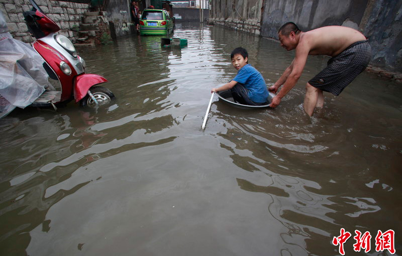 Rainstorms hit Jinan, Shandong Province, on July 8, 2012. In the picture, peopel try to float across a street which is flooded during the rainstorms.