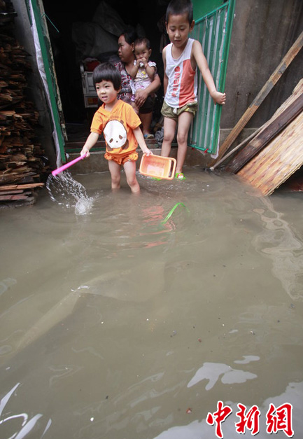 Rainstorms hit Jinan, Shandong Province, on July 8, 2012. In the picture, children try to float across a street which is flooded during the rainstorms.