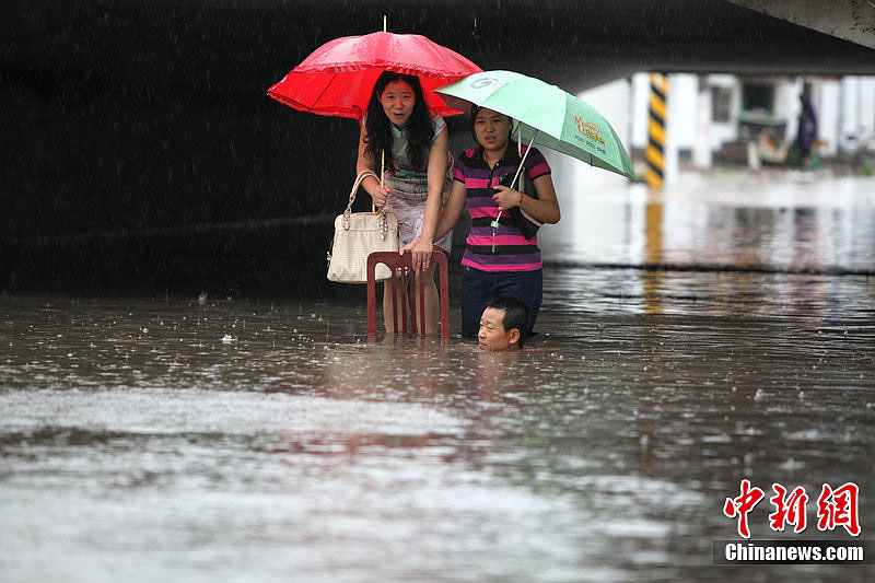 Rainstorms hit Lianyungang, Jiangsu Province, on July 8, 2012. In the picture people try to float across a street which is flooded during the rainstorms. 