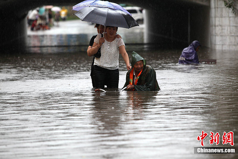 Rainstorms hit Lianyungang, Jiangsu Province, on July 8, 2012. In the picture people try to float across a street which is flooded during the rainstorms. 