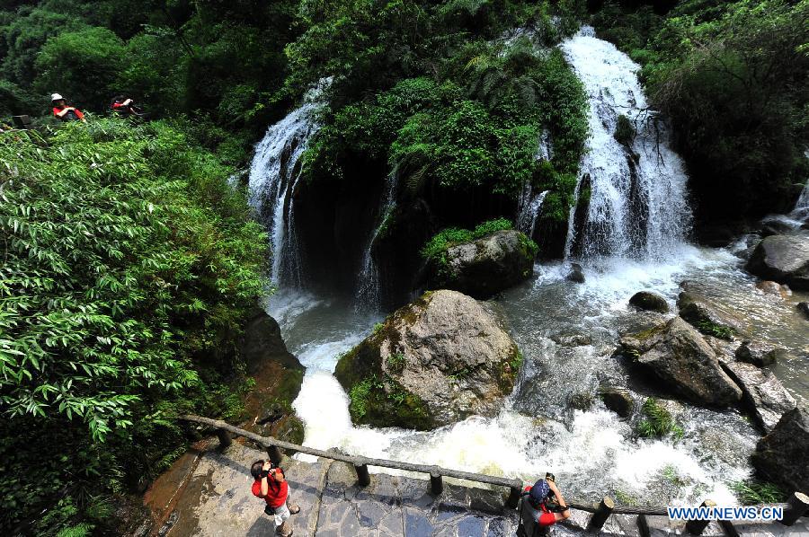 Tourists visit a waterfall at a resort in the Xiling Gorge, the easternmost of the Three Gorges along the Yangtze River, in Yichang, central China's Hubei Province, July 8, 2012. Tourism revenue has soared in recent years as the resort incorporated both natural scenery and ethnic culture in its operation. (Xinhua/Chen Haining) 