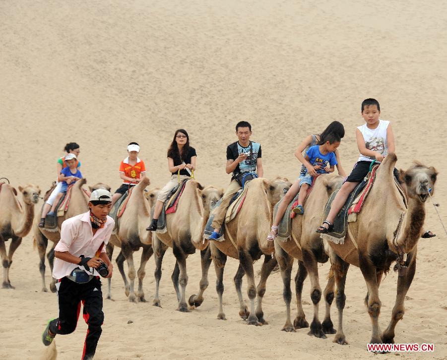 Tourists ride camels in the Sand Lake scenic area in Pingluo County, northwest China's Ningxia Hui Autonomous Region, July 8, 2012. Scenic spots in the deserts of Ningxia have entered the high season of tourism in recent days. [Xinhua/Li Ran]