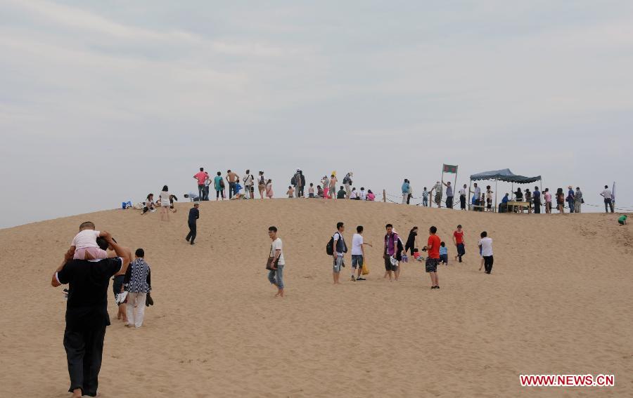 Tourists visit the Sand Lake scenic area in Pingluo County, northwest China's Ningxia Hui Autonomous Region, July 8, 2012. Scenic spots in the deserts of Ningxia have entered the high season of tourism in recent days. [Xinhua/Li Ran]