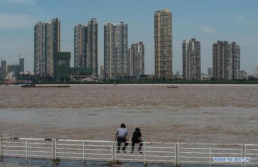 Two citizens see torrential water on the bank of the Yangtze River in Wuhan, capital of central China's Hubei Province, July 9, 2012. [Xinhua]