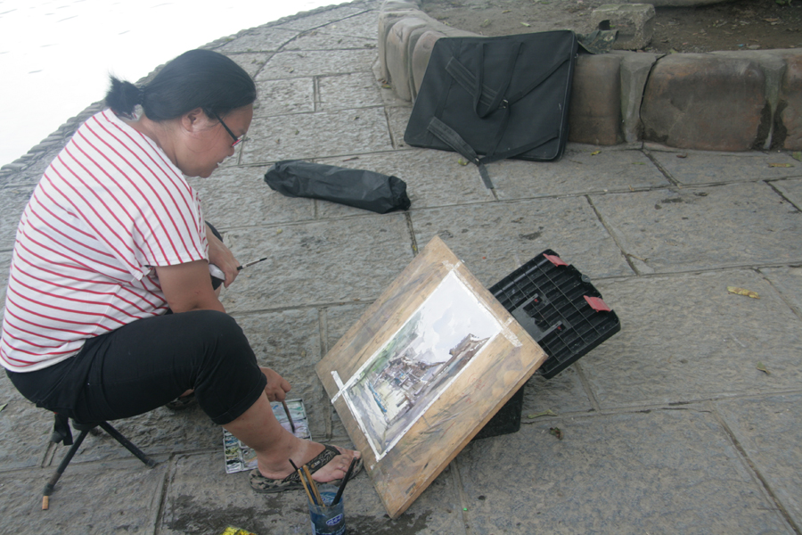 A female visitor paints a depiction of Biancheng Town. [CnDG by Jiao Meng]