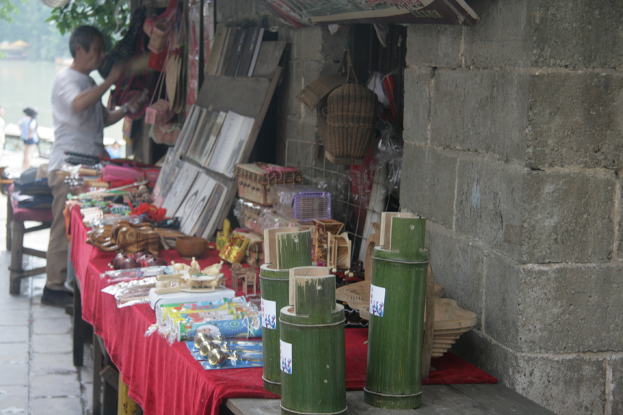 A vendor sells local products. The green objects are “Tu Fei,” which are bamboo tubes filled with home-made liquor. [CnDG by Jiao Meng]