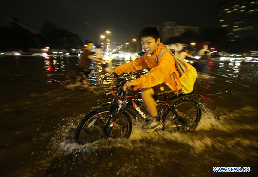 A child rides a bicycle at the flooded Xuanwumen crossroads in downtown Beijing, capital of China, July 10, 2012. Beijing was hit by a torrential rain on Tuesday evening.