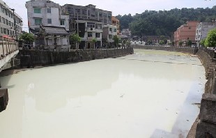 A 1-kilometer stretch of the Quxi River in Zhejiang province, turned white as emulsion leaked into the tributary from a nearby chemical factory. [Xinhua]