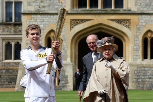 In this handout image provided by LOCOG, Queen Elizabeth II and Prince Philip, Duke of Edinburgh look on as Olympic torchbearer 074 Phillip Wells holds the Olympic Flame at Windsor Castle on day 53 of the London 2012 Olympic Torch Relay on July 10, 2012 in Windsor, England. The Olympic Flame is now on day 53 of a 70-day relay involving 8,000 torchbearers covering 8,000 miles. 
