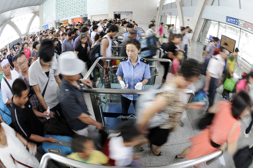 Passengers are examined tickets in the Yinchuan Railway Station on July 11. The volume of passenger traffic reaches its climax as school vacation and summer workers recruiting start in July. [Xinhua photo] 