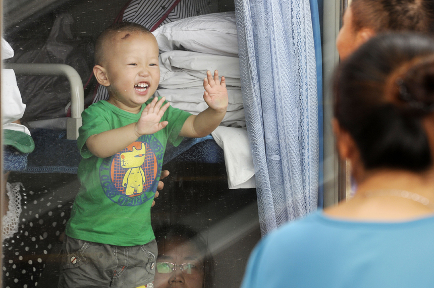 A child says goodbye to his parents at the Yinchuan Railway Station on July 11. The volume of passenger traffic reaches its climax as school vacation and summer workers recruiting start in July. [Xinhua photo] 