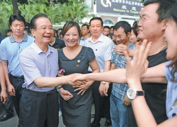 Premier Wen Jiabao chats with residents in Chengdu, Sichuan province, on Friday. Wen focused on the need to maintain and boost economic growth during a three-day inspection tour of the province. [China Daily]
