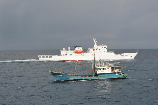 A Chinese fishing boat fishes under the escort of Chinese fishery administration vessels, Yuzheng 310, in waters off the Fiery Cross Reef in the South China Sea on July 15. A Chinese fleet comprised of 30 fishing boats departed from Sanya port of South China's Hainan province on July 12. After sailing for more than 70 hours around the clock, they arrived at the destination at 3:56 pm Sunday. They are expected to stay for five to ten days for fishing. [Xinhua]
