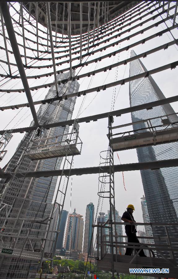 A worker joins in the installation of curtain walls for the Shanghai Tower under construction in the Pudong District of east China's Shanghai, July 15, 2012. The Shanghai Tower, to be the tallest building in Shanghai upon completion, started to be installed with curtain walls in recent days.