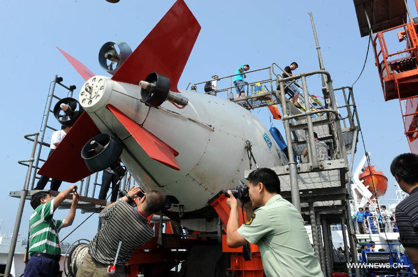 Visitors take photos of Jiaolong, China's manned submersible, on Xiangyanghong-9 ship in Qingdao, east China's Shandong Province, July 16, 2012. China's manned submersible Jiaolong has successfully completed its program of deep sea dives, with a sixth and final dive to 7,000 meters in the Mariana Trench in the Pacific Ocean on June 30. 