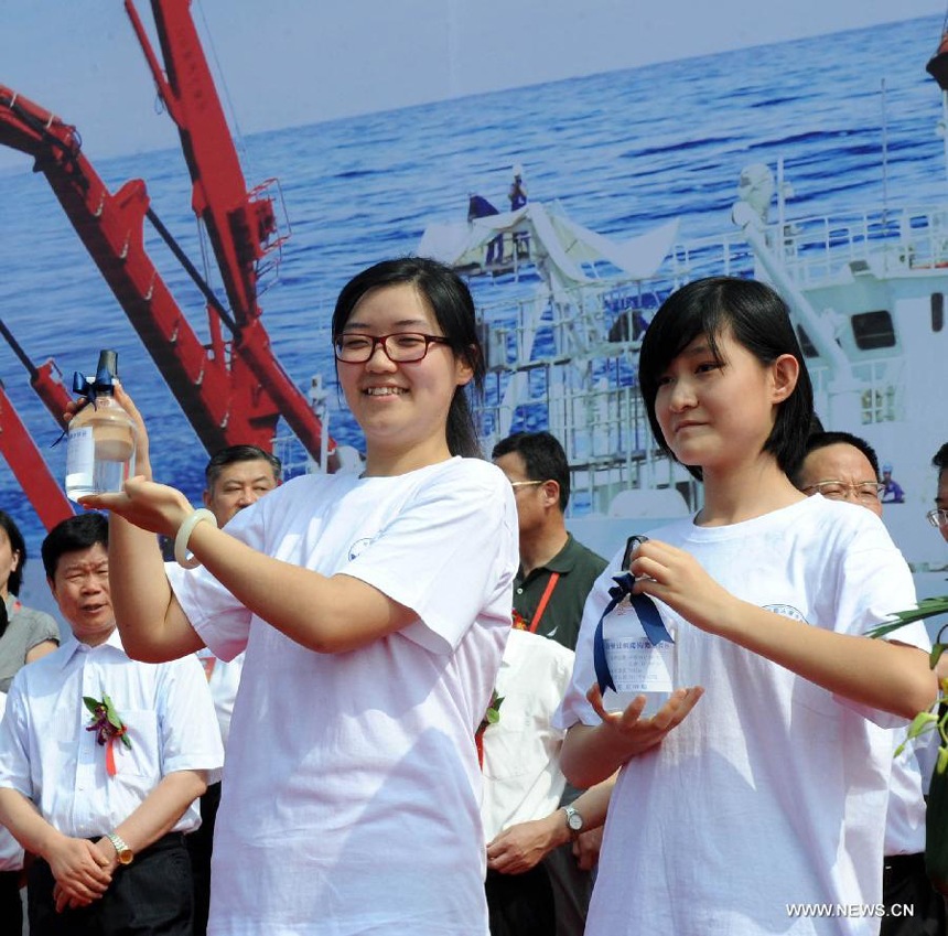 Two middle school students present two bottles of seawater sample collected from the deep sea by China's manned submersible Jiaolong on the Xiangyanghong-9 ship in Qingdao, east China's Shandong Province, July 16, 2012. China's manned submersible Jiaolong has successfully completed its program of deep sea dives, with a sixth and final dive to 7,000 meters in the Mariana Trench in the Pacific Ocean on June 30. 