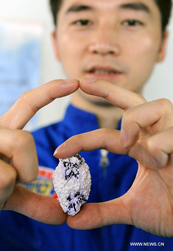 Oceanaut Fu Wentao of China's manned submersible Jiaolong shows a foam ball which was pressed to be egg-shape in a deep sea research activity on Xiangyanghong-9 ship in Qingdao, east China's Shandong Province, July 16, 2012. China's manned submersible Jiaolong has successfully completed its program of deep sea dives, with a sixth and final dive to 7,000 meters in the Mariana Trench in the Pacific Ocean on June 30.