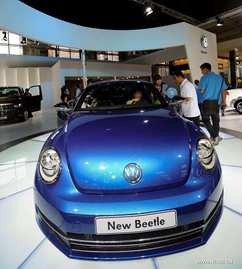 Visitors experience the newly designed Volkswagen Beetle in the 9th China (Changchun) International Automobile Expo in Changchun, capital of northeast China's Jilin Province, July 16, 2012. The new Beetle is expected to go on sale officially in this autumn with a price of 200,000 - 300,000 yuan (about 31,340-47,010 U.S. dollars).