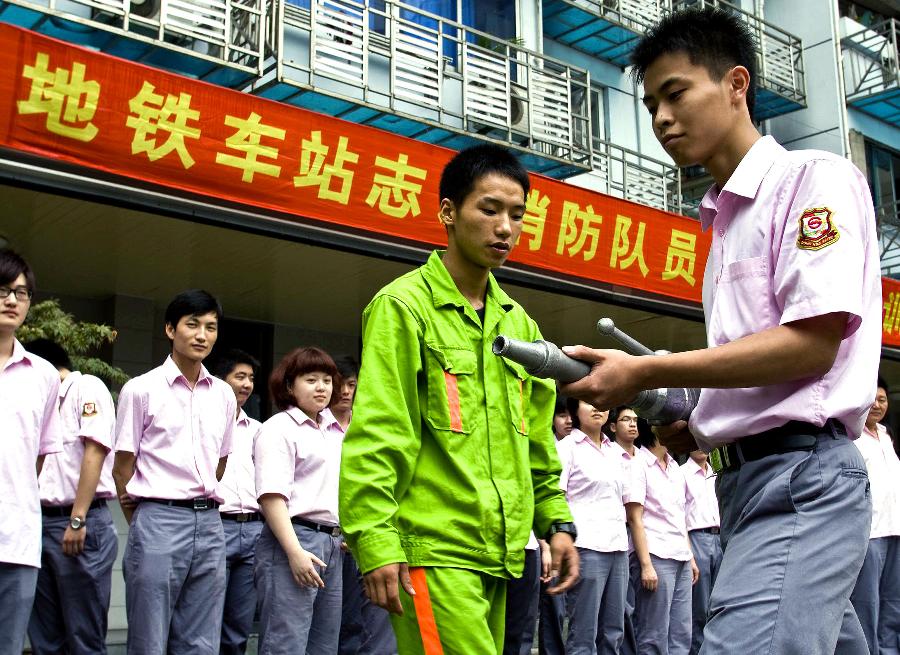 A metro staff member practices using fire hoses in Shanghai, east China, July 17, 2012. Firefighters of Huangpu District provided a fire safety training to over 600 fire fighting volunteers of Shanghai Metro on Tuesday, to enhance those metro staff's emergency response capability. (Xinhua/Chen Fei) 