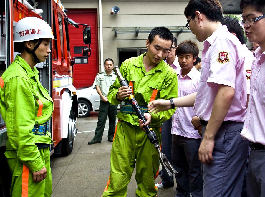 A firefighter demonstrates fire fighting equipment to metro staff in Shanghai, east China, July 17, 2012. Firefighters of Huangpu District provided a fire safety training to over 600 fire fighting volunteers of Shanghai Metro on Tuesday, to enhance those metro staff's emergency response capability. (Xinhua/Chen Fei) 