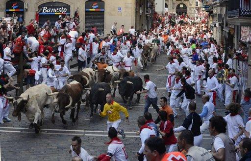 Runners sprint alongside Torrehandilla fighting bulls on Mercaderes street during the final running of the bulls at the San Fermin festival in Pamplona July 14, 2012. 