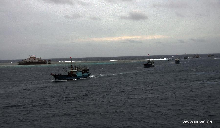 Fishing vessels sail past a building on Meiji Reef of south China Sea on July 20, 2012. The fleet of 30 boats, including a 3,000-tonne lead boat carrying fresh water, fuel and other supplies, sailed into the lagoon of Meiji Reef to take shelter from storm at about 6 p.m. Friday. The fleet has sailed past Sanya and Yongshu, Zhubi and Meiji reefs. [Xinhua]