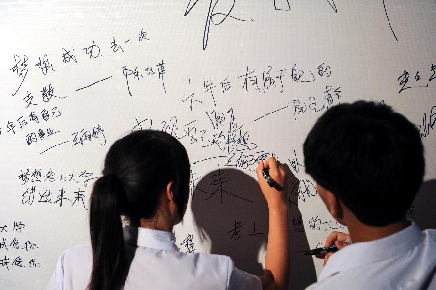 Students from the both sides of the Taiwan Strait write down their wishes as they attend a coming-of-age ceremony in Fenghua, east China's Zhejiang Province, July 20, 2012. A coming-of-age ceremony was held here Friday, in which 30 students from southeast China's Taiwan and 50 mainland students took part. [Xinhua]