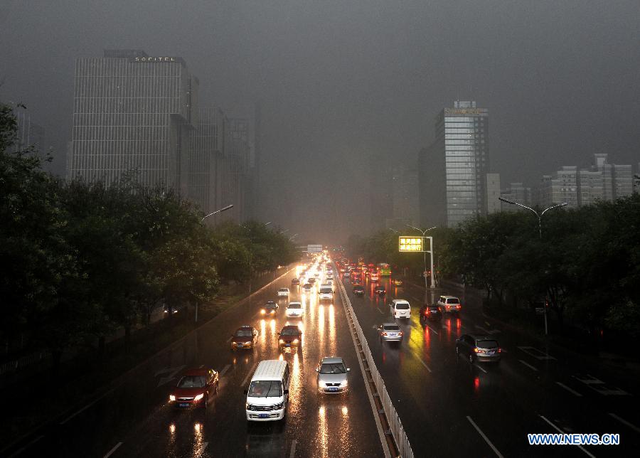 Vehicles turn on head lights while running amid heavy rain in Beijing, capital of China, July 21, 2012. A downpour hits Beijing at noon on Saturday. [Xinhua]