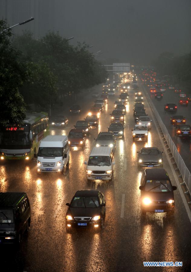 Vehicles turn on head lights while running amid heavy rain in Beijing, capital of China, July 21, 2012. A downpour hits Beijing at noon on Saturday. [Xinhua]