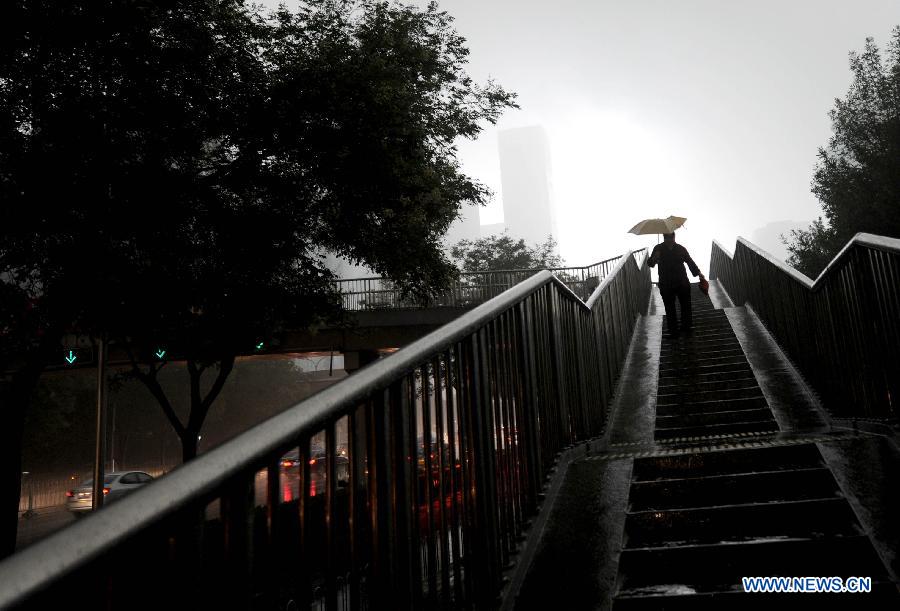 A pedestrian walks down an overbridge amid heavy rain in Beijing, capital of China, July 21, 2012. A downpour hits Beijing at noon on Saturday. [Xinhua]