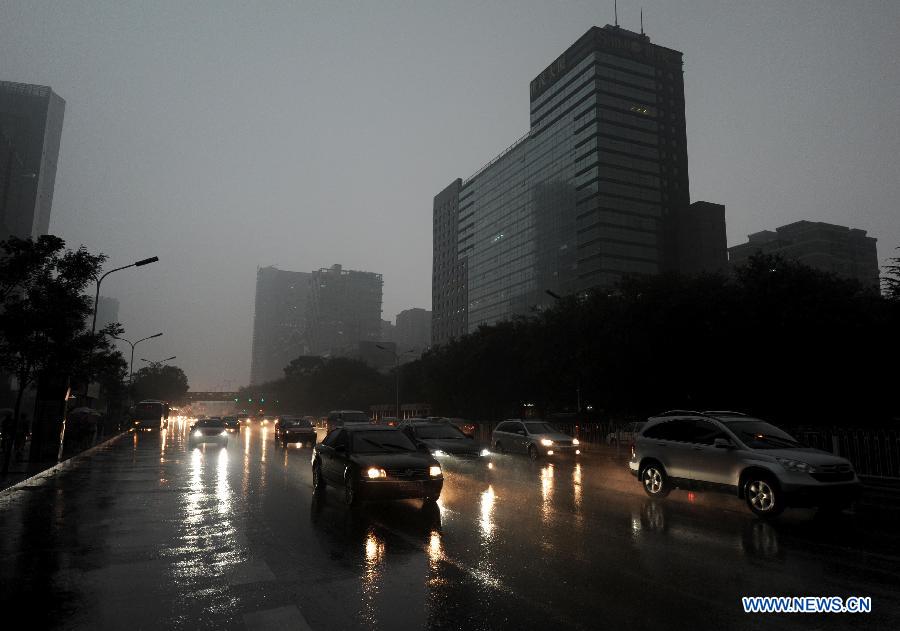 Vehicles turn on head lights while running amid heavy rain in Beijing, capital of China, July 21, 2012. A downpour hits Beijing at noon on Saturday. [Xinhua]