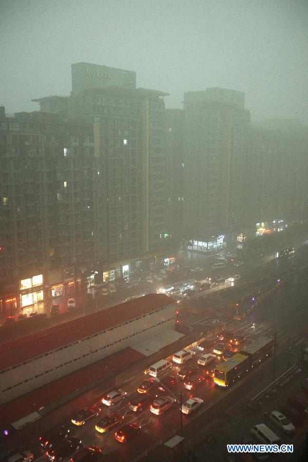 Motorcars have to turn lights on while running amid heavy rain in Beijing, capital of China, July 21, 2012. A downpour hits Beijing at noon on Saturday. [Xinhua]