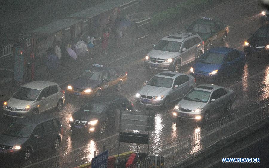 Motorcars have to turn lights on while running amid heavy rain in Beijing, capital of China, July 21, 2012. A downpour hits Beijing at noon on Saturday. [Xinhua]