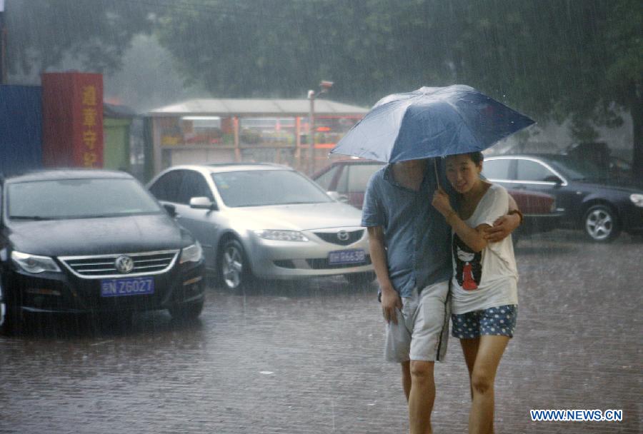 Pedestrians hold an umbrella as they walk amid heavy rain in Beijing, capital of China, July 21, 2012. A downpour hits Beijing at noon on Saturday. [Xinhua]