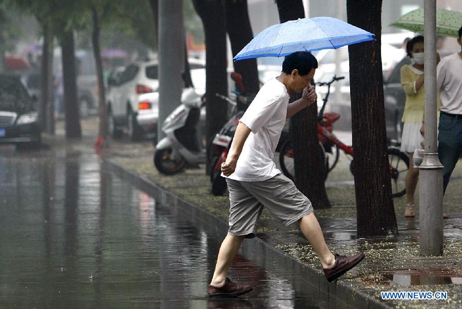 A pedestrian holds an umbrella as he walks amid heavy rain in Beijing, capital of China, July 21, 2012. A downpour hits Beijing at noon on Saturday. [Xinhua]