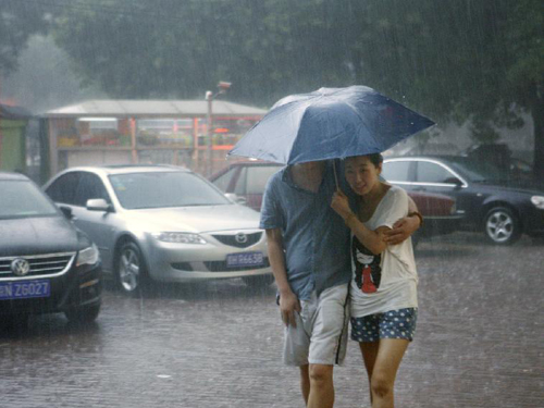 Pedestrians hold an umbrella as they walk amid heavy rain in Beijing, capital of China, July 21, 2012. A downpour hits Beijing at noon on Saturday. [Xinhua] 