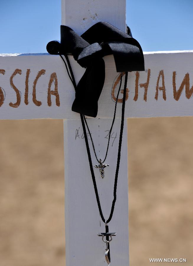 A black riband is tied on the cross at a memorial near the Century 16 movie theater in Aurora, Colorado, July 22, 2012. Twelve people were killed and 59 others injured at a Batman movie premier, where a lone, heavily armed gunman burst into a packed theater in a suburb 10 miles east of Denver during the wee hours of Friday. (Xinhua/Yang Lei) 