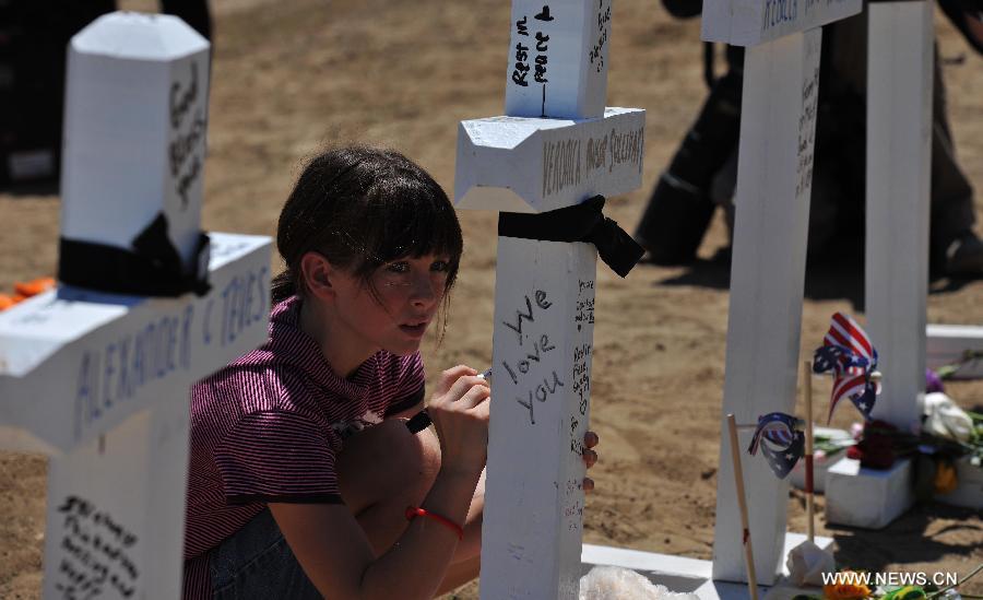 A girl grieves at a memorial near the Century 16 movie theater in Aurora, Colorado, July 22, 2012. Twelve people were killed and 59 others injured at a Batman movie premier, where a lone, heavily armed gunman burst into a packed theater in a suburb 10 miles east of Denver during the wee hours of Friday. (Xinhua/Yang Lei) 