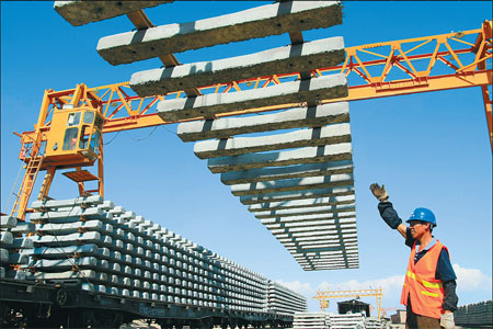 A worker guides a crane loading rails onto a freight train at the construction site of Hami-Lop Nur Railway in the Xinjiang Uygur autonomous region on Thursday. 