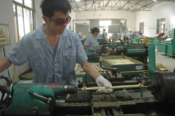 Meng Jirui, a student at Liaocheng University, processes a copper pipe at an automobile parts factory in Liaocheng, Shandong province, recently. The university recommended 80 students to work at local factories for two months during the summer vacation.[Photo / China Daily] 