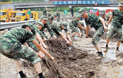 Rescuers clean up mud on the Beijing-Hong Kong-Macau Expressway yesterday, two days after the torrential rain that hit Beijing, leaving 37 people dead. This section of the expressway was where more than 80 vehicles became submerged in up to 6 meters of water. The heavy rain has claimed 95 lives across China, including the 37 Beijing victims.