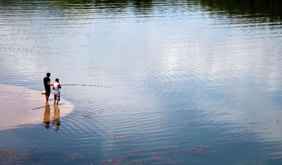 People fish at the Yanqi Lake in the Huairou District of Beijing, capital of China, July 23, 2012.