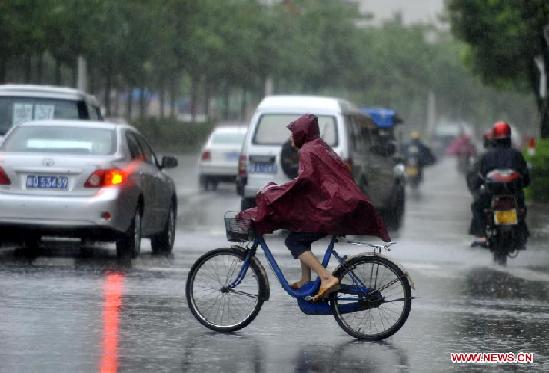 A citizen rides a bike while vehicles move against rainstorm on a street in Yangjiang, south China's Guangdong Province, July 24, 2012. Typhoon Vicente landed in Chixi Town of Taishan City in Guangdong early Tuesday.[ Photo / Xinhua ]