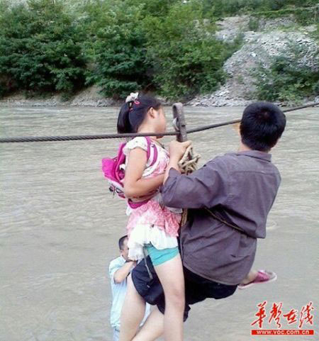 Students in Wen County, Gansu province, use a cable to cross the Bailong River on their way to school. [Photo: voc.com.cn]