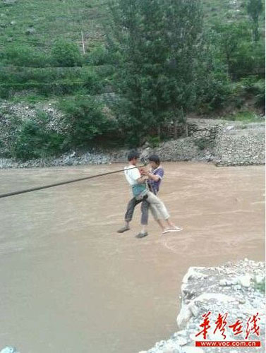 Students in Wen County, Gansu province, use a cable to cross the Bailong River on their way to school. [Photo: voc.com.cn]