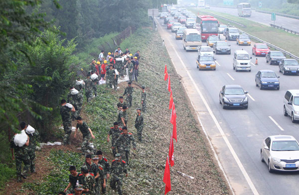 Hundreds of rescuers carry sandbags to build a 2-km long floodwall at a section of the Beijing-Hong Kong-Macao Expressway in Beijing's Fengtai district on Wednesday.[ Photo / China Daily ]