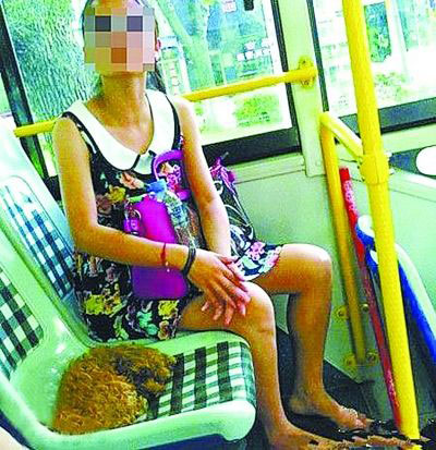 An unidentified female passenger lets her dog take a seat on a bus in Ningbo, Zhejiang province on July 25, 2012. [Photo: Yangtse Evening Newspaper]