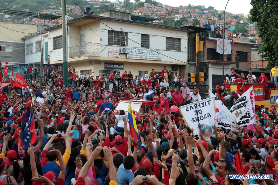 Venezuelan President and presidential candidate Hugo Chavez (C) greets his supporters during a caravan at El Valle parish, in Caracas, capital of Venezuela, on July 26, 2012. Chavez and opposition candidate Henrique Capriles will compete in the presidential election on Oct. 7, 2012. (Xinhua/AVN) 